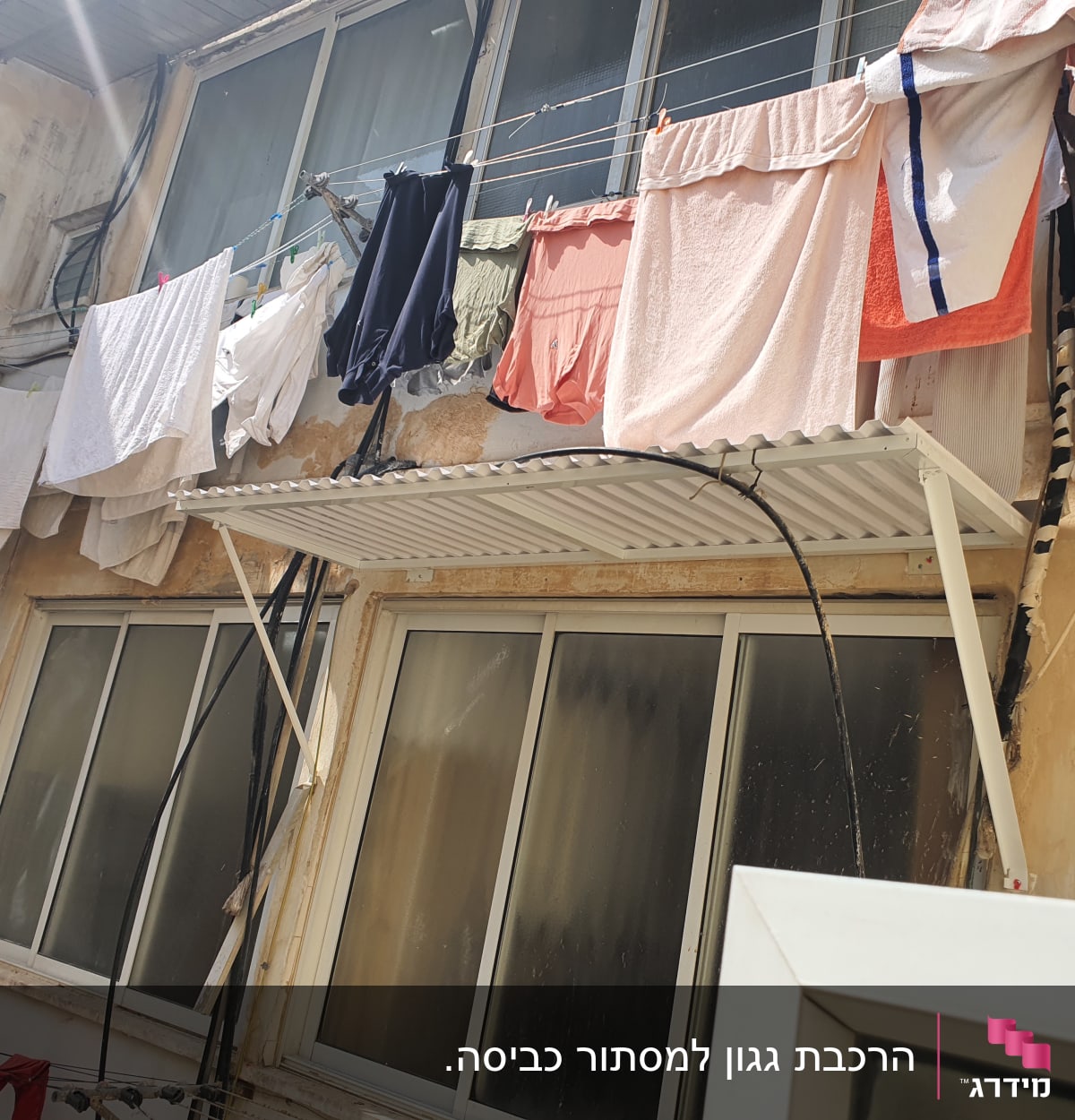 גגון אלומיניום מעל חלון עם כביסה תלויה